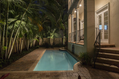Modelo de piscina alargada exótica pequeña rectangular en patio trasero con adoquines de hormigón