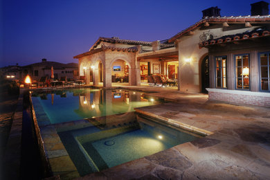 Пример оригинального дизайна: прямоугольный бассейн-инфинити среднего размера на заднем дворе в средиземноморском стиле с джакузи и покрытием из каменной брусчатки