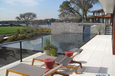 Mittelgroßer Moderner Infinity-Pool hinter dem Haus in rechteckiger Form mit Wasserspiel und Natursteinplatten in New York