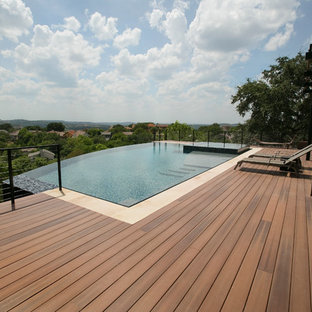 Ispirazione per una grande piscina a sfioro infinito design rettangolare dietro casa con una vasca idromassaggio e pedane