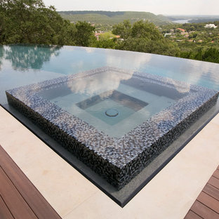 Idee per una grande piscina a sfioro infinito minimal rettangolare dietro casa con una vasca idromassaggio e pedane