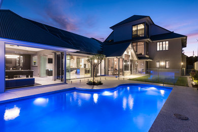 Diseño de piscina natural minimalista grande a medida en patio trasero con adoquines de hormigón