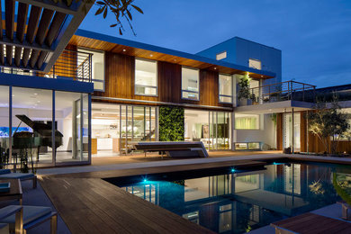 Idée de décoration pour une grande piscine design avec une terrasse en bois et une cour.