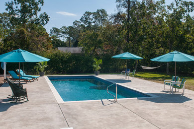 Foto de piscina alargada clásica grande rectangular en patio trasero con losas de hormigón