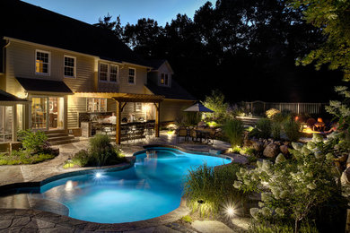 Ejemplo de piscina natural de estilo americano pequeña a medida en patio trasero con adoquines de piedra natural