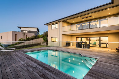 Diseño de piscina alargada minimalista de tamaño medio rectangular en patio trasero con entablado