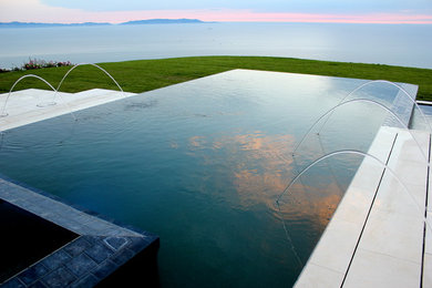 Ispirazione per una piscina rettangolare dietro casa con fontane e pavimentazioni in pietra naturale