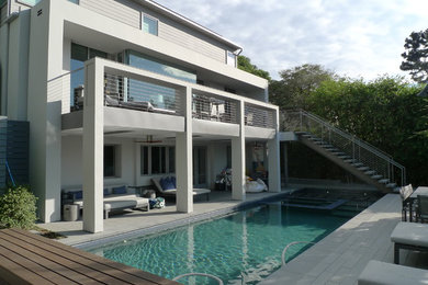 Modelo de piscina moderna de tamaño medio rectangular en patio trasero con adoquines de hormigón