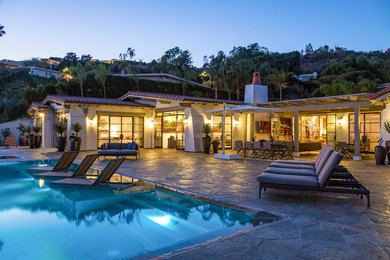 Großer Mediterraner Infinity-Pool hinter dem Haus in rechteckiger Form mit Natursteinplatten in Los Angeles