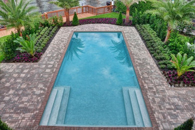 Imagen de piscina alargada tradicional grande rectangular en patio trasero con suelo de baldosas
