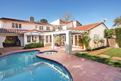 Example of a mid-sized classic backyard brick and kidney-shaped natural hot tub design in Los Angeles