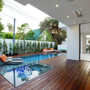 Immagine di una piscina a sfioro infinito minimalista rettangolare di medie dimensioni e dietro casa con pedane
