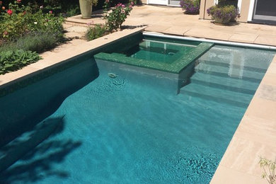 Modelo de piscinas y jacuzzis clásicos renovados de tamaño medio rectangulares en patio trasero con suelo de baldosas