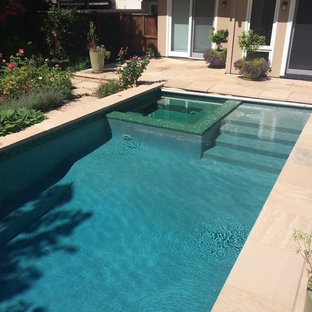 Modelo de piscinas y jacuzzis clásicos renovados, de tamaño medio, rectangulares, en patio trasero, con suelo de baldosas