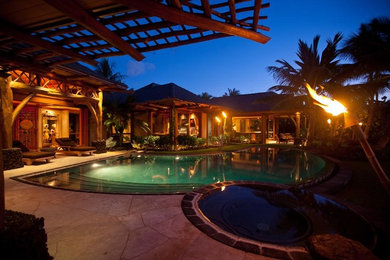 Foto di una piscina a sfioro infinito tropicale personalizzata dietro casa con una vasca idromassaggio e pavimentazioni in pietra naturale