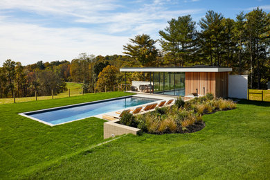This is an example of a midcentury rectangular swimming pool in New York with a pool house.