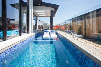 Foto de piscina alargada de tamaño medio rectangular en patio trasero con entablado