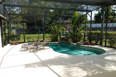 Inspiration for a large back custom shaped lengths swimming pool in Orlando with a water feature and concrete paving.