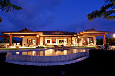 Ejemplo de piscina con fuente infinita de estilo americano grande a medida en patio trasero con adoquines de piedra natural