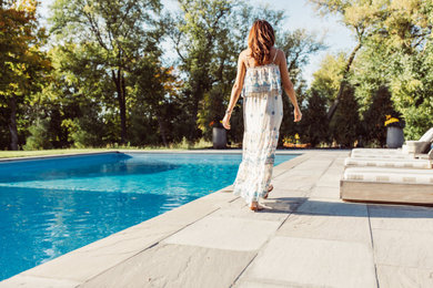Diseño de piscina moderna extra grande rectangular en patio trasero con adoquines de piedra natural