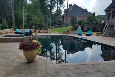 Ejemplo de piscina clásica renovada de tamaño medio a medida en patio trasero con adoquines de hormigón