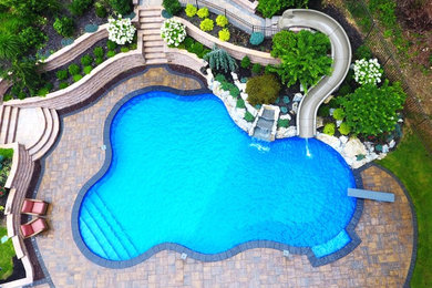 Water slide - large backyard concrete paver and custom-shaped water slide idea in New York