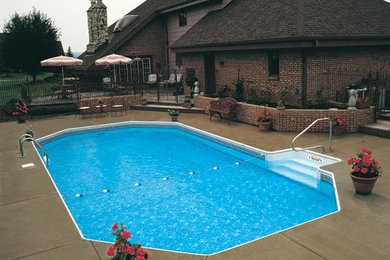 Modelo de piscina clásica grande rectangular en patio trasero con adoquines de hormigón