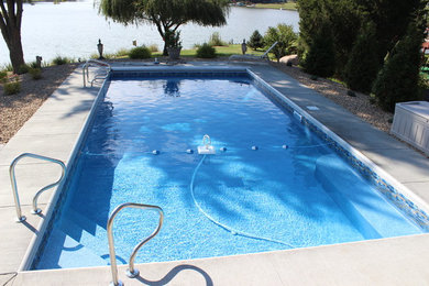 Diseño de piscina con fuente moderna grande rectangular en patio trasero con suelo de hormigón estampado