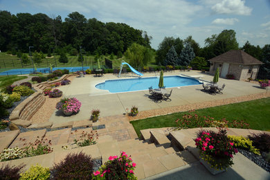 Ejemplo de piscina con tobogán minimalista grande rectangular en patio trasero con losas de hormigón