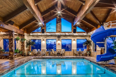This is an example of a medium sized rustic indoor rectangular swimming pool with a pool house and natural stone paving.