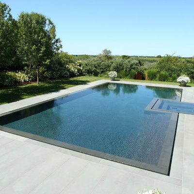 Example of a trendy stone and custom-shaped infinity hot tub design in New York