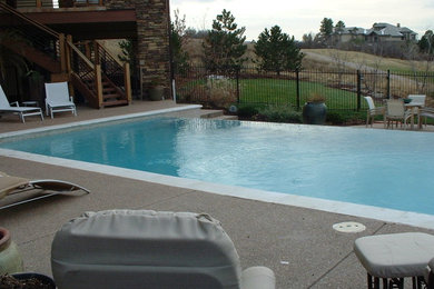 Imagen de piscina con fuente infinita clásica de tamaño medio rectangular en patio trasero con losas de hormigón