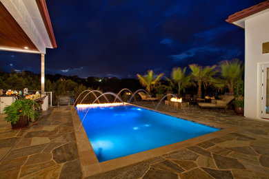 Modelo de piscina infinita rústica de tamaño medio rectangular en patio trasero con adoquines de piedra natural
