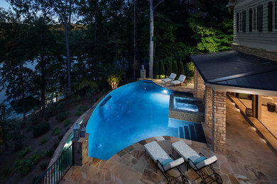 Immagine di un'ampia piscina a sfioro infinito tradizionale personalizzata dietro casa con una dépendance a bordo piscina e pavimentazioni in mattoni