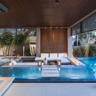 Esempio di un'ampia piscina a sfioro infinito moderna personalizzata dietro casa con pedane