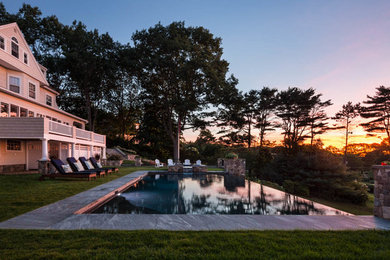 Mid-sized elegant backyard rectangular and stone infinity hot tub photo in Portland Maine