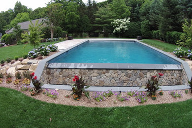 Imagen de piscina con fuente infinita clásica renovada grande rectangular en patio trasero con adoquines de piedra natural