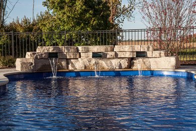 Diseño de piscina con fuente natural moderna de tamaño medio a medida en patio trasero con adoquines de piedra natural