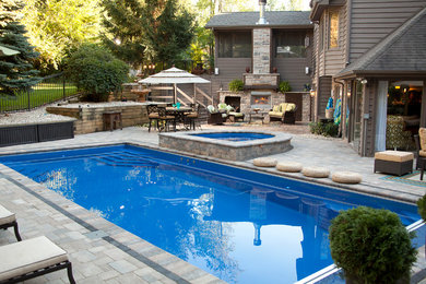 Modelo de piscina con fuente natural de tamaño medio rectangular en patio trasero con adoquines de piedra natural