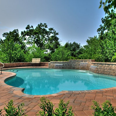 Example of a mid-sized tuscan backyard concrete paver and custom-shaped lap pool fountain design in Other