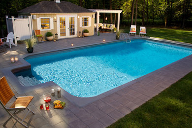 Ejemplo de casa de la piscina y piscina campestre grande rectangular en patio trasero con adoquines de hormigón