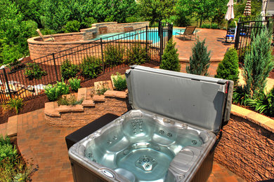 Large tuscan backyard concrete paver and custom-shaped lap hot tub photo in Other