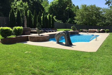 Ejemplo de piscina alargada tradicional de tamaño medio rectangular en patio trasero con losas de hormigón