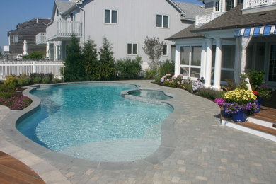 Идея дизайна: большой бассейн произвольной формы на заднем дворе в морском стиле с мощением клинкерной брусчаткой