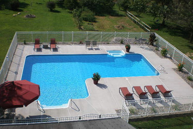 Diseño de piscina alargada tradicional grande en forma de L en patio trasero con losas de hormigón