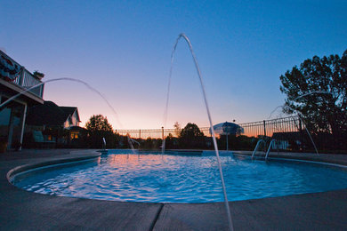 Foto di una grande piscina naturale classica a "C" dietro casa con fontane e pavimentazioni in cemento