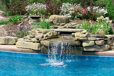 Foto de piscina con fuente tradicional grande en patio trasero con adoquines de hormigón