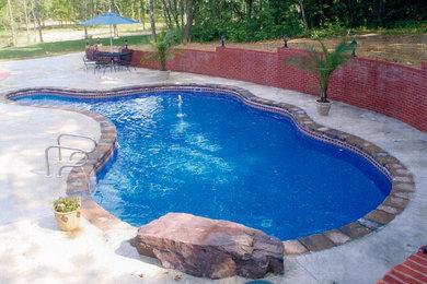Medium sized traditional back custom shaped natural swimming pool in New York with stamped concrete.