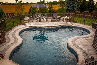 Ejemplo de piscina con fuente natural minimalista de tamaño medio a medida en patio trasero con adoquines de piedra natural