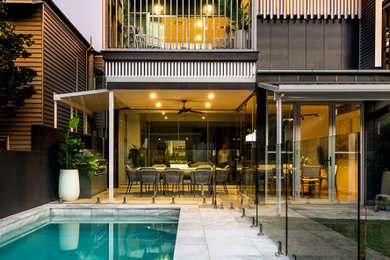 Diseño de piscina con fuente alargada contemporánea de tamaño medio rectangular en patio trasero con adoquines de piedra natural